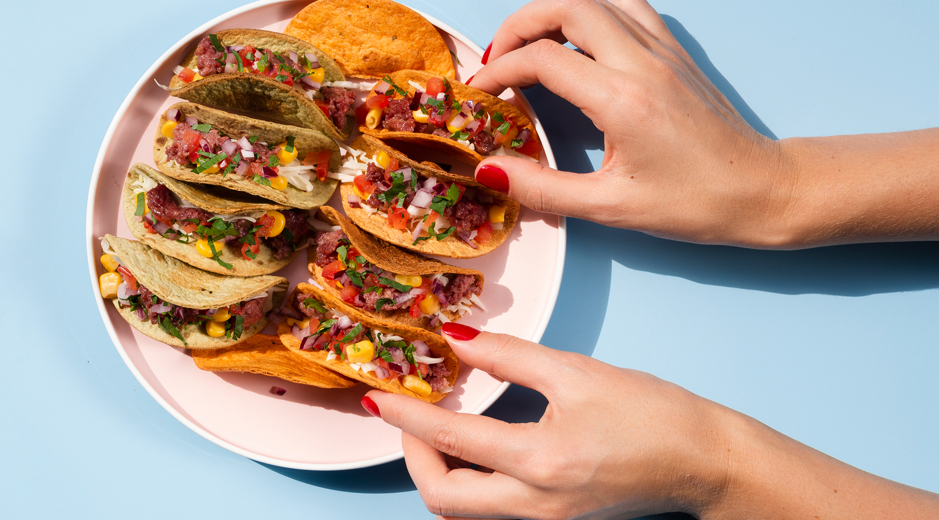 Tacos garnis de bœuf, maïs, oignons et coriandre servis sur une assiette.